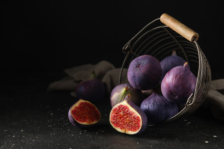 Basket with fresh ripe figs on black backgroundの写真素材