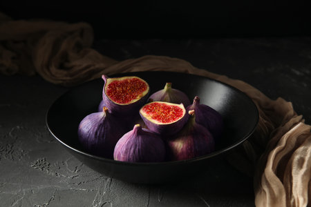 Bowl with fresh ripe figs on black background