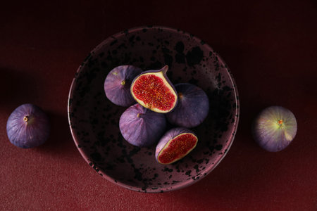 Bowl with fresh ripe figs on red backgroundの写真素材