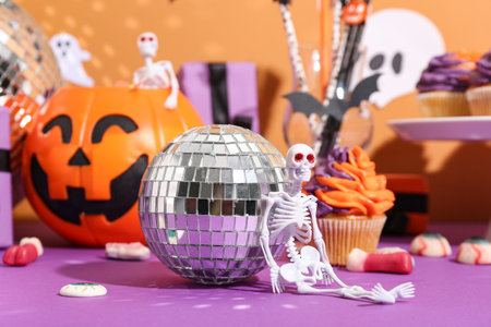 Disco ball with skull, cupcakes and Halloween decor on color backgroundの写真素材