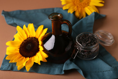 Jug of oil, sunflower and jar with seeds on brown backgroundの写真素材