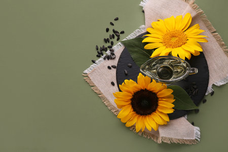 Gravy boat of oil with sunflowers and seeds on green backgroundの写真素材