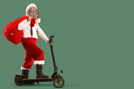 Santa Claus with bag full of gifts riding electric scooter on green backgroundの写真素材