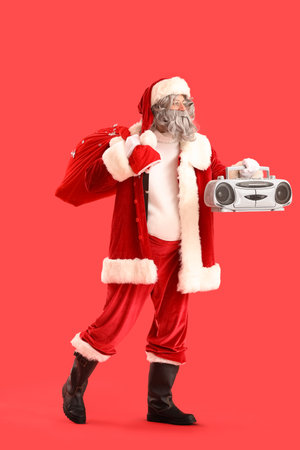 Santa Claus with bag full of gifts and boombox on red backgroundの写真素材