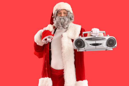 Santa Claus with bag full of gifts and boombox on red backgroundの写真素材
