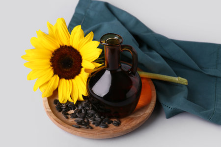 Jug of oil with sunflower and seeds on gray backgroundの写真素材