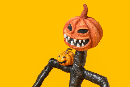 Spooky Halloween monster with pumpkins on yellow background, closeupの写真素材
