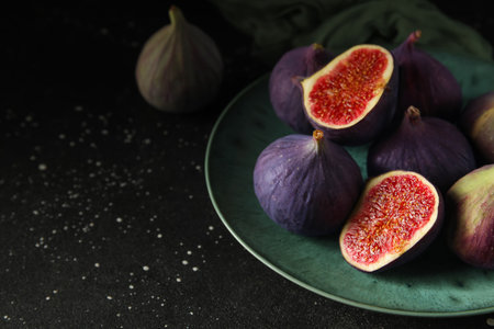 Plate with fresh ripe figs on black background, closeupの写真素材
