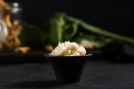 Ceramic bowl of horseradish sauce on black grunge background, closeupの写真素材