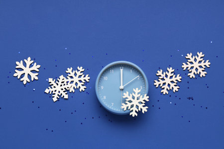 Composition with alarm clock, decorative snowflakes and confetti on blue backgroundの写真素材