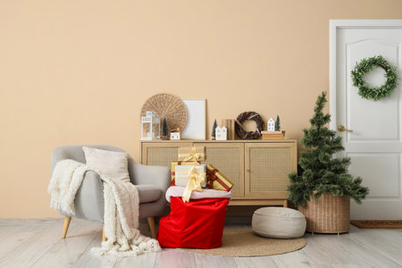 Interior of festive living room with gray armchair, bag full of gifts and Christmas treeの写真素材