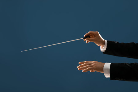 Hands of male conductor with baton on blue background