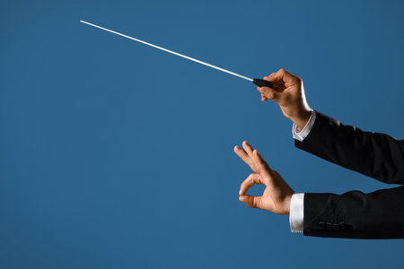 Hands of male conductor with baton showing OK on blue backgroundの写真素材
