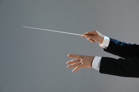 Hands of male conductor with baton on gray backgroundの写真素材