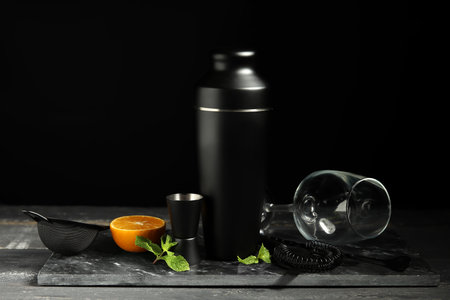 Bartender kit and ingredients for cocktail on gray wooden table near black wallの写真素材