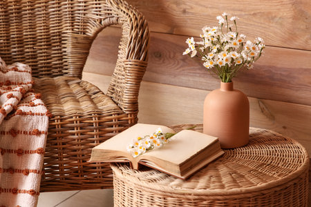 Vase with artificial flowers and open book on wicker coffee table in stylish living room, closeupの写真素材