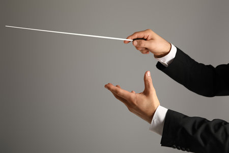 Hands of male conductor with baton on gray backgroundの写真素材