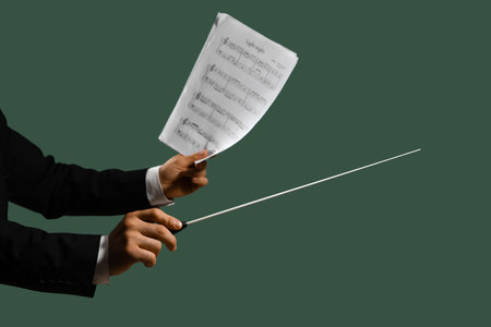 Hands of male conductor with baton and note sheet on green backgroundの写真素材