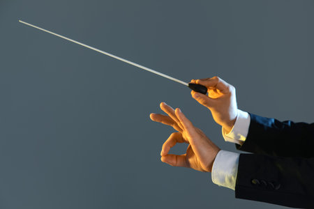 Hands of male conductor with baton showing OK on gray backgroundの写真素材