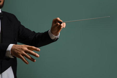 Hands of male conductor with baton on green backgroundの写真素材