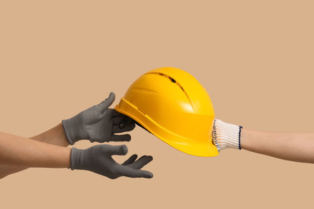 Hands with hardhat on beige backgroundの写真素材
