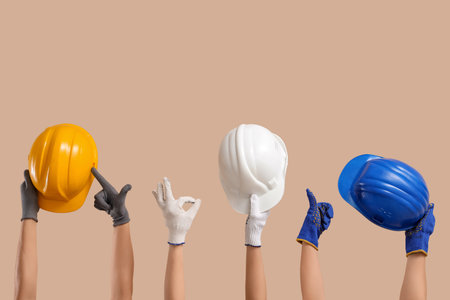 Hands with hardhats gesturing on beige backgroundの写真素材