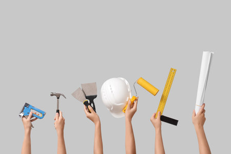 Hands with hardhat and construction tools on gray backgroundの写真素材