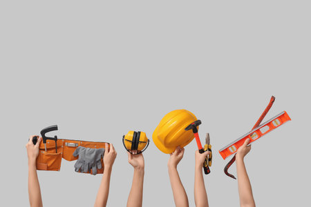 Hands with hardhat and construction tools on gray backgroundの写真素材