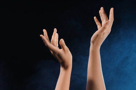 Female hands with blue energy on black backgroundの写真素材