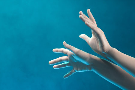 Female hands with blue energy on black backgroundの写真素材