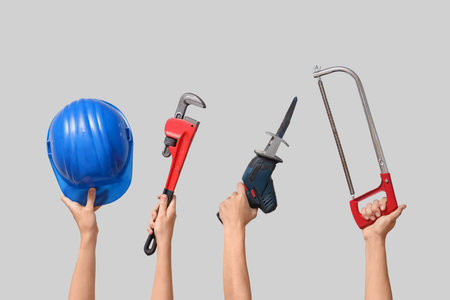 Hands with hardhat and construction tools on gray backgroundの写真素材