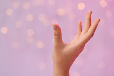 Female hand with energy sparkles on pink backgroundの写真素材