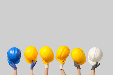 Hands with hardhats on gray backgroundの写真素材