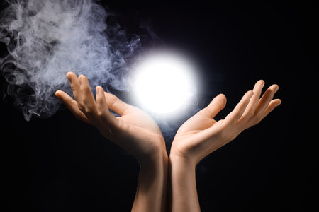 Female hands with ball of energy on black backgroundの写真素材