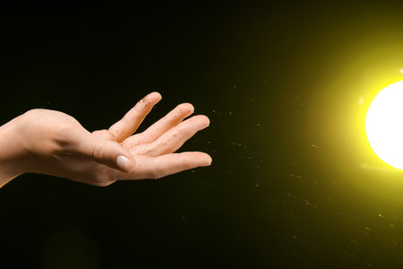 Female hand with energy sparkles and yellow light on black backgroundの写真素材