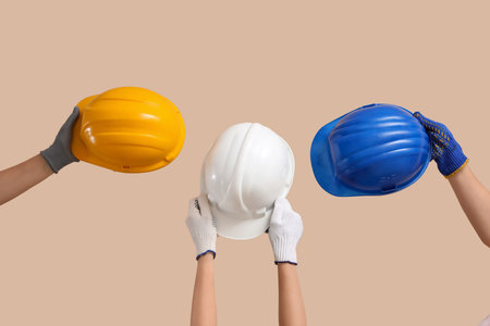 Hands with hardhats on beige backgroundの写真素材