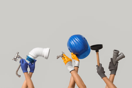 Hands with hardhat and plumber supplies on gray backgroundの写真素材