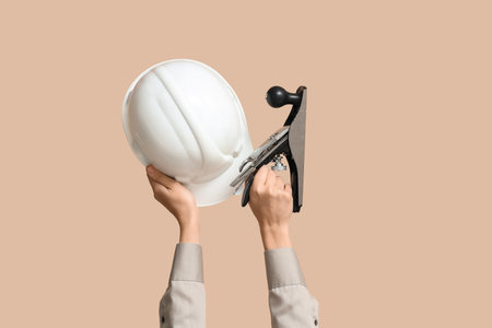 Hands with hardhat and handheld planer on beige backgroundの写真素材
