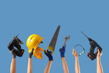 Hands with hardhat and construction tools on blue background