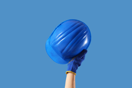Hand with hardhat on blue backgroundの写真素材