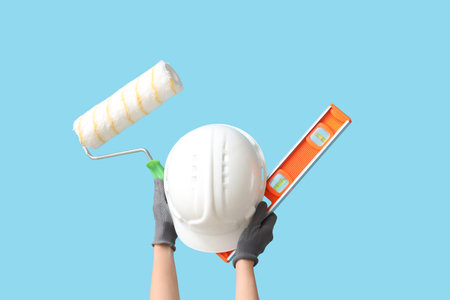 Hands with hardhat and construction tools on blue backgroundの写真素材
