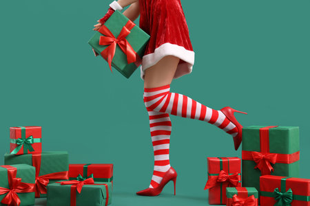 Woman in Santa costume with Christmas gifts on green backgroundの写真素材