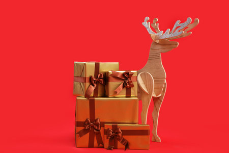 Christmas gifts and wooden reindeer on red backgroundの写真素材