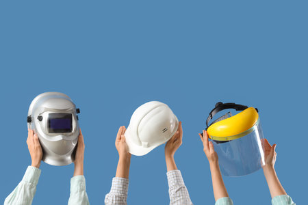 Hands with hardhat, face shield and welding mask on blue backgroundの写真素材