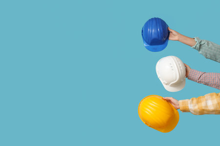 Hands with hardhats and construction tools on blue backgroundの写真素材