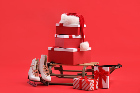 Sled with Christmas gifts and ice skates on red backgroundの写真素材