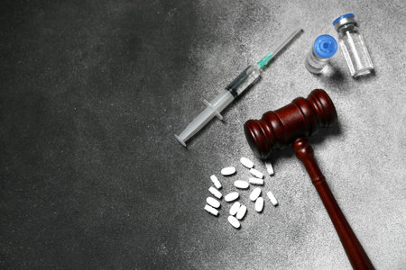 Judge gavel with pills, ampules and syringe on grunge gray background. Concept of health care reformの写真素材