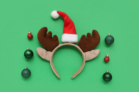 Christmas reindeer antlers headband with Santa hat and baubles on green backgroundの写真素材