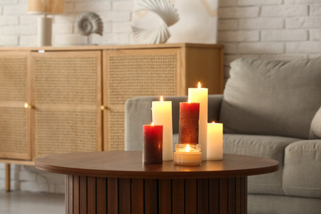 Burning candles on wooden table in living room, closeupの写真素材