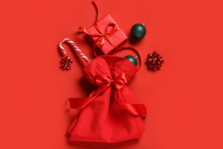 Composition with Santa bag, Christmas balls, candy cane and gift box on red backgroundの写真素材